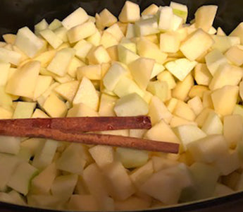 chopped apples and cinnamon sticks in crock pot